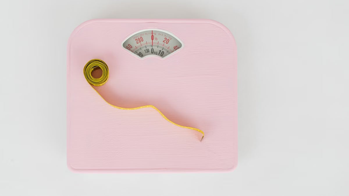 Top view of floor scales for weight control and measuring tape for controlling body shapes on white background